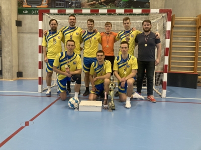Futbola komanda zālē, dzeltenzilos sporta tērpos ar futbola vārtiem fonā