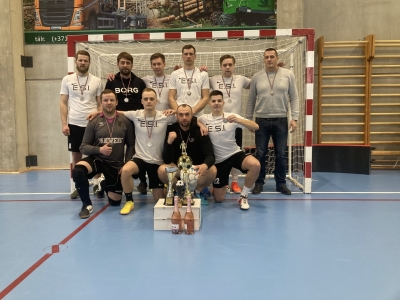 Futbola komanda zālē, baltos sporta tērpos ar futbola vārtiem fonā