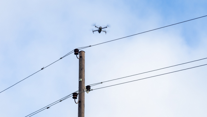 Elektrības stabs ar dronu fonā