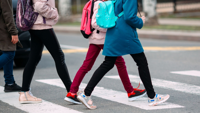 Skolēni iet pāri gājēju pārejai