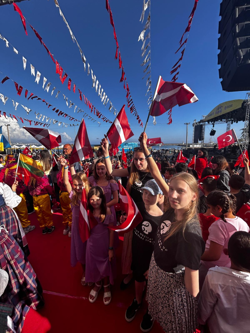 Delegācija ar Latvijas karogiem festivālā